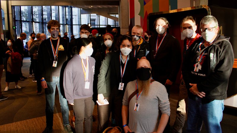 Ten Catalyst staff members wearing masks are standing in a large even toom.