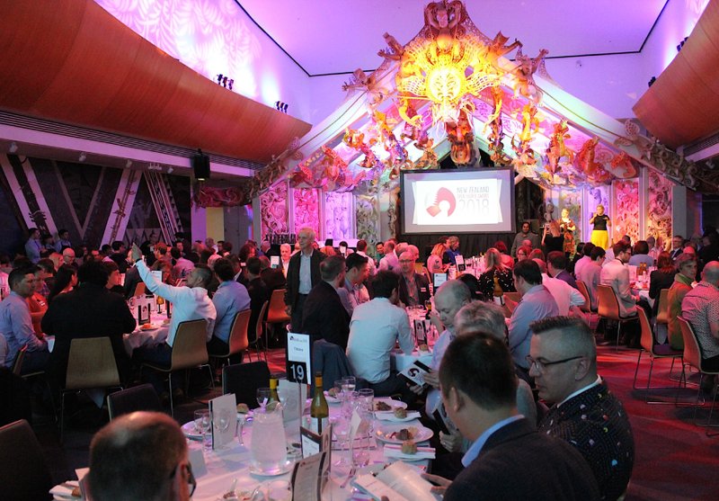 A crowd of people sitting at tables during an awards presentation at the Te Papa marae