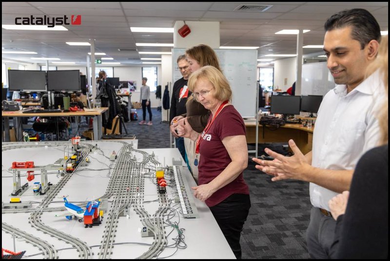 A few people are looking at a large and complex Lego train set up.